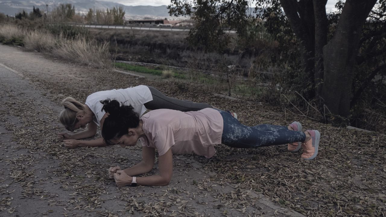Dos mujeres haciendo el ejercicio de planca en un parque