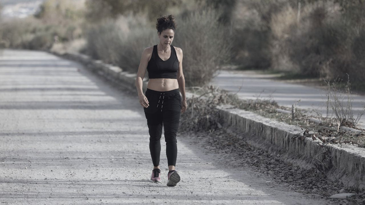 Mujer andando en mitad del campo mirando abajo