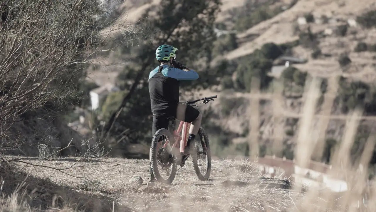 hombre en bicicleta en mitad del campo tomando suplementación deportiva