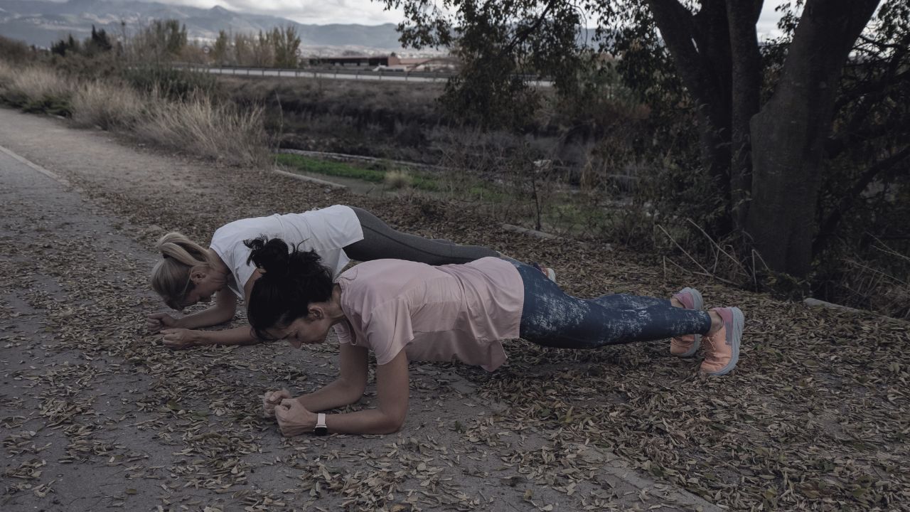 Dos mujeres haciendo el ejercicio de plancha en un parque