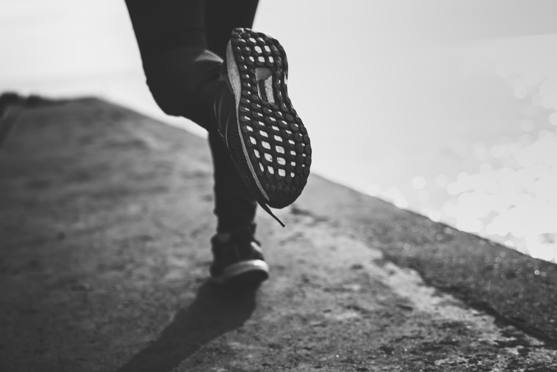 persona corriendo sobre asfalto en blanco y negro