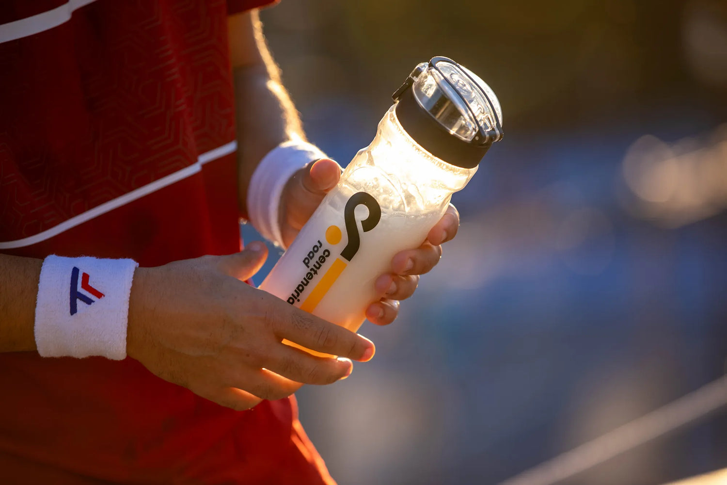 Manos de un tenista sujetando un shaker de Centenarian Road durante una pausa de entrenamiento