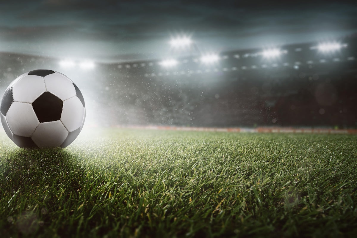 Balón de fútbol sobre el césped de un campo en la cabecera de la página de suplementos para futbolistas de Centenarian Roa